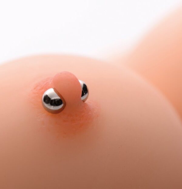 Silver magnetic orb nipple clamps worn on a nipple to show their size