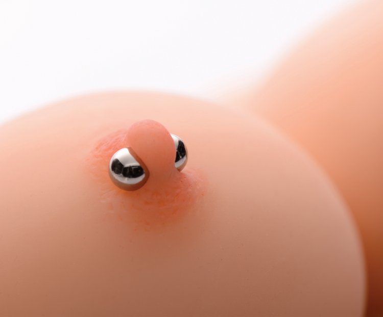 Silver magnetic orb nipple clamps worn on a nipple to show their size
