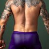 Back view of a model in the Male Power Eggplant crossover short in purple wet-look