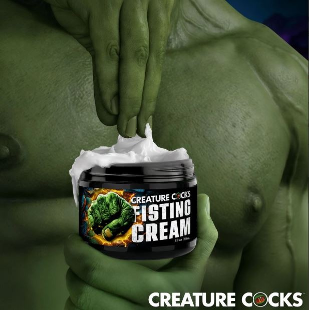 Green creature hand scooping Creature Cocks Fisting Cream from the jar