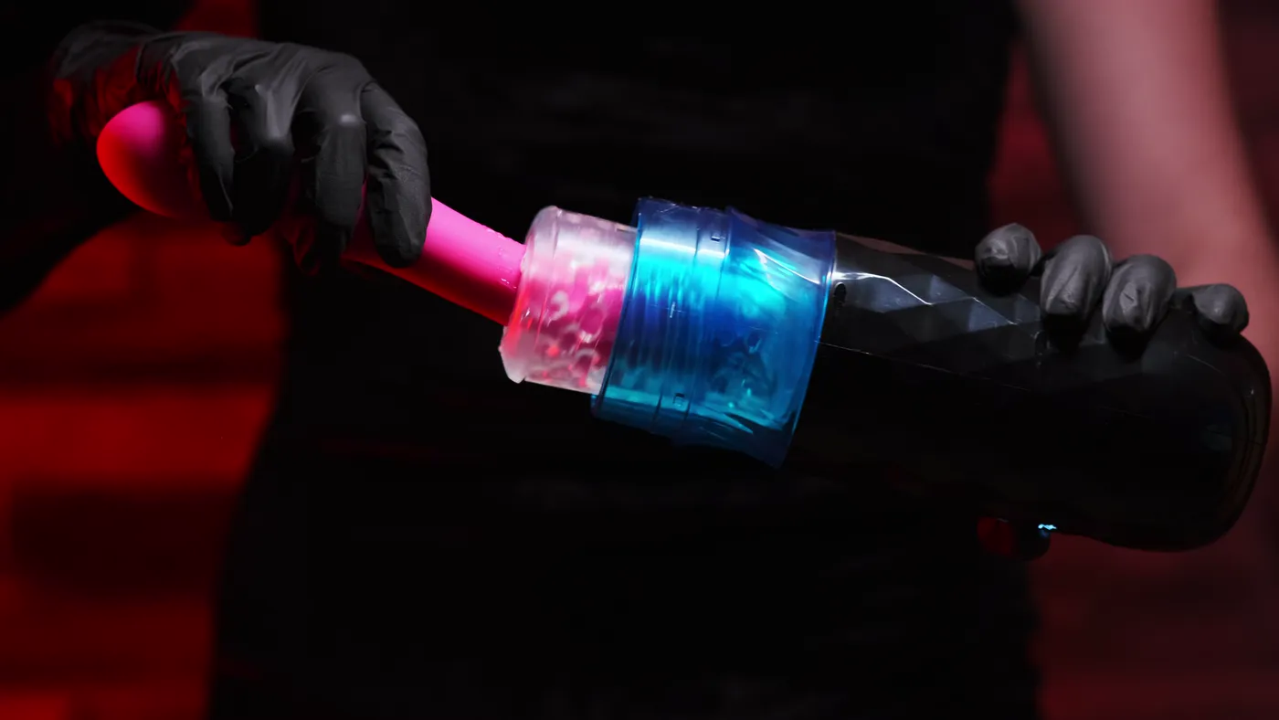 Pink wand vibrator and blowjob machine stroker sex toys held in black gloves